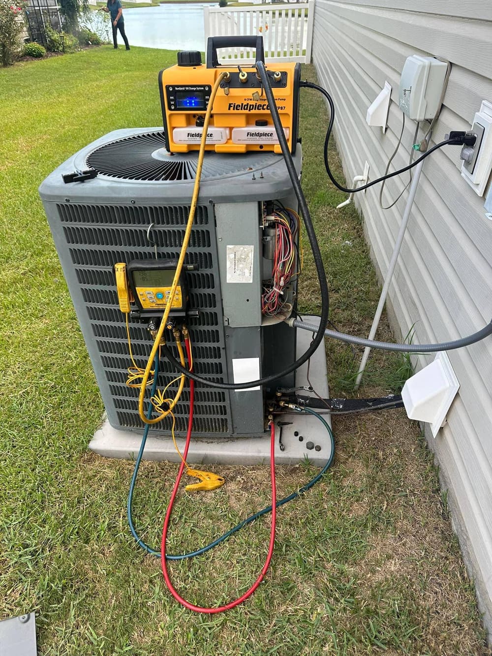 Outdoor condenser with a Fieldpiece gauge set and recovery gear connected