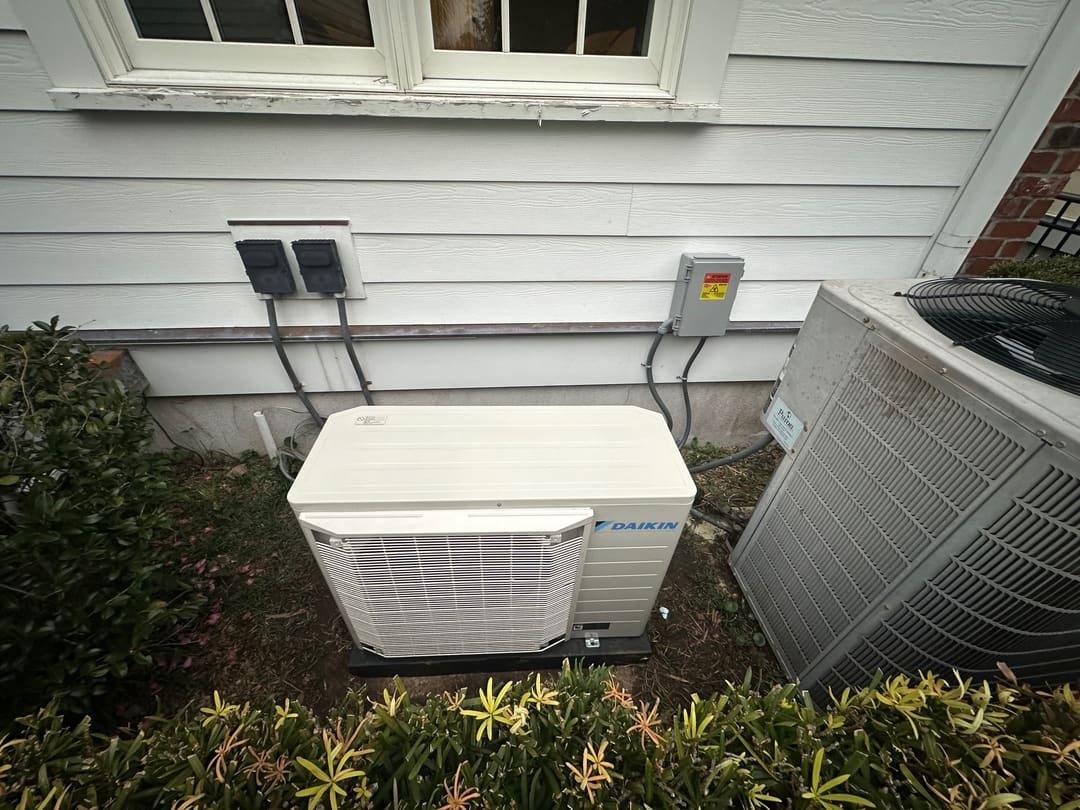 Daikin outdoor unit and a second condenser beside a house wall