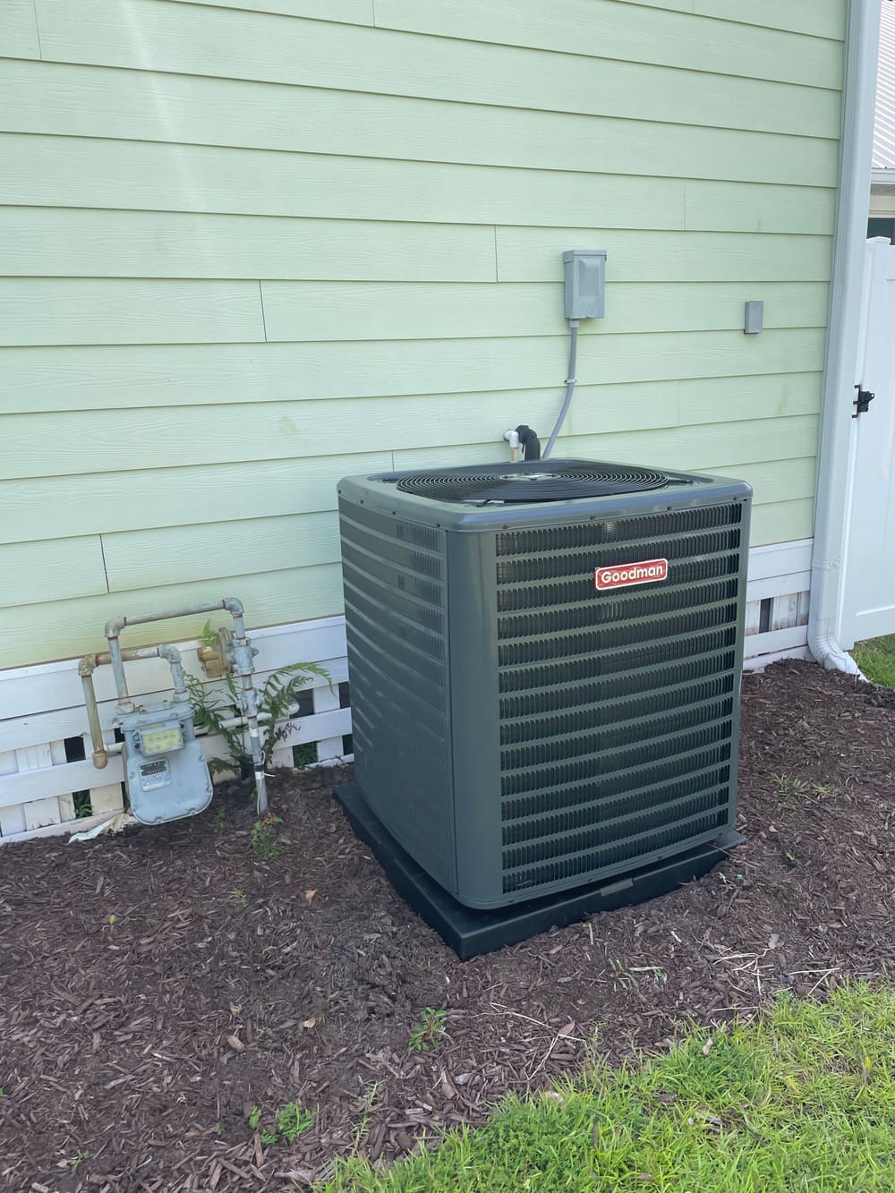 New outdoor condenser beside a green-sided house
