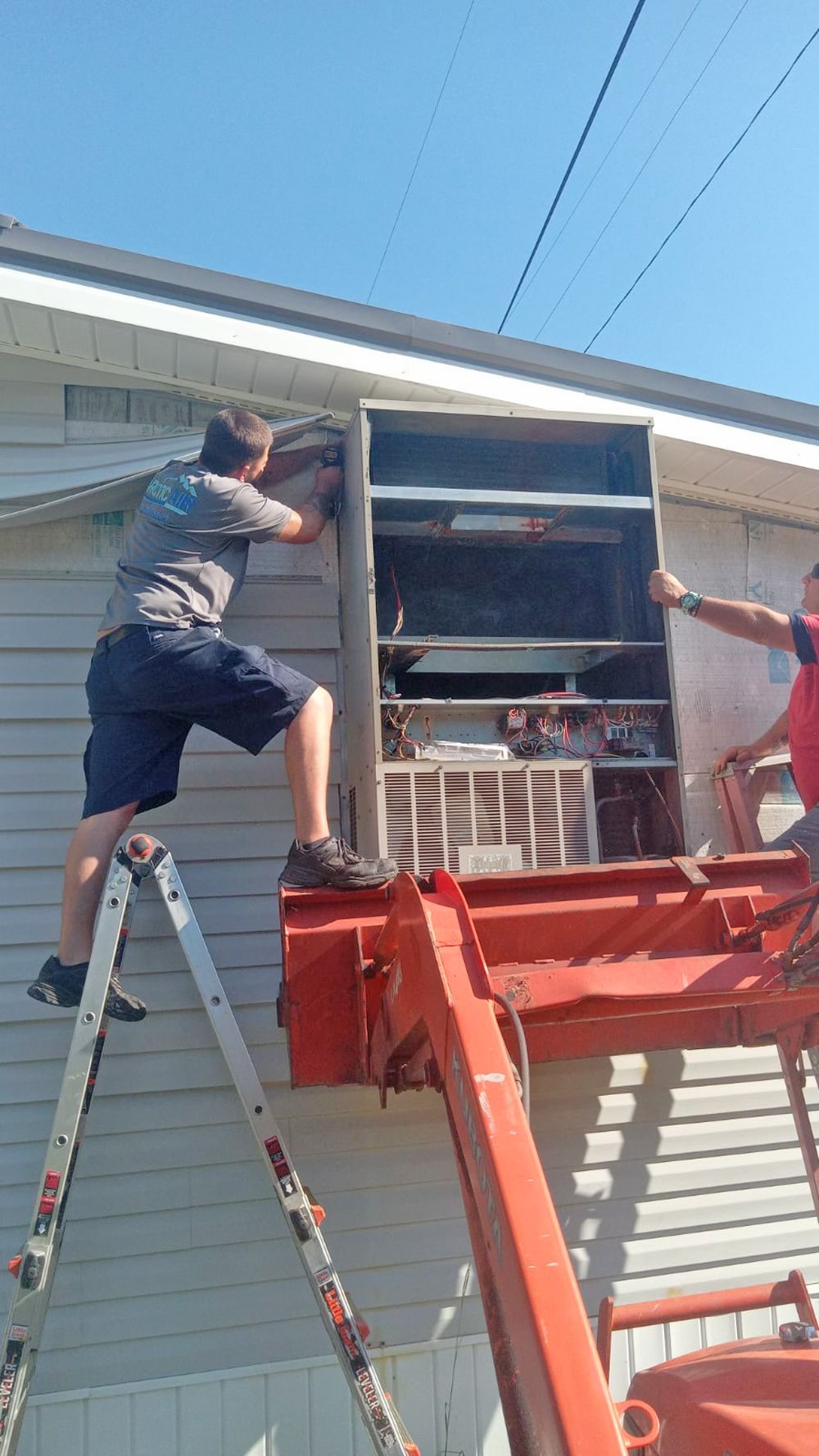 Arctic Air crew removing a wall unit with a tractor bucket